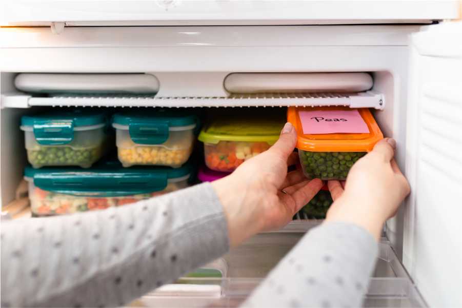 An open freezer with an neatly organised assortment of clear containers containing vegetables