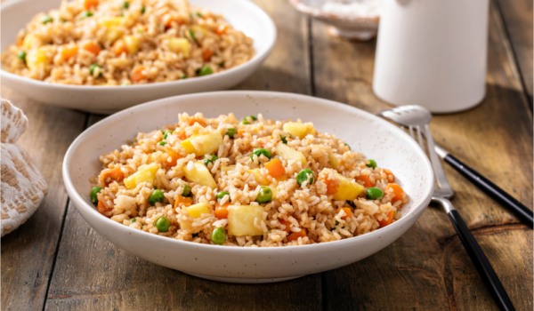 Two bowls of fried rice sitting on a wooden table