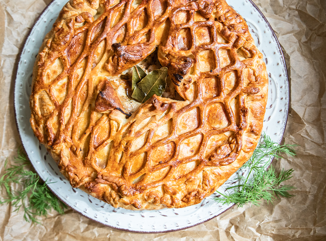 Top view of a Chicken and Leek Puff Pie sitting on a plate on a table