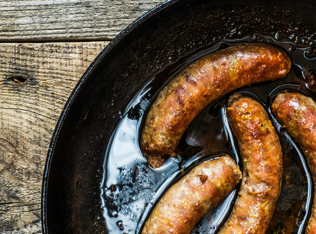 Photo of 4 sausages cooking in a pan