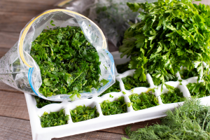 Bag of herbs on a table with an ice tray full of chopped herbs.